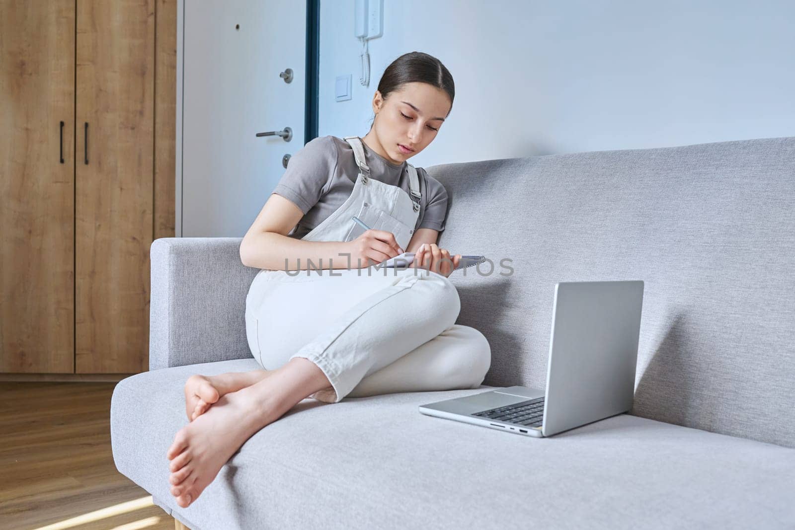 Teen girl at home on couch using laptop by VH-studio