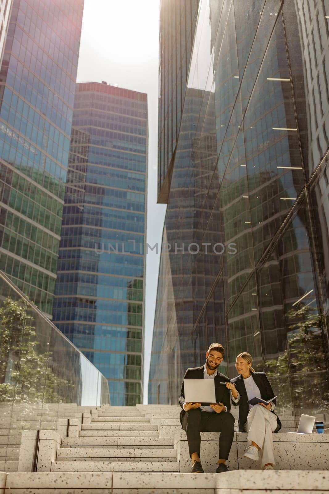 Focused businessman and businesswomen working outdoor on laptop with new startup project by Yaroslav_astakhov