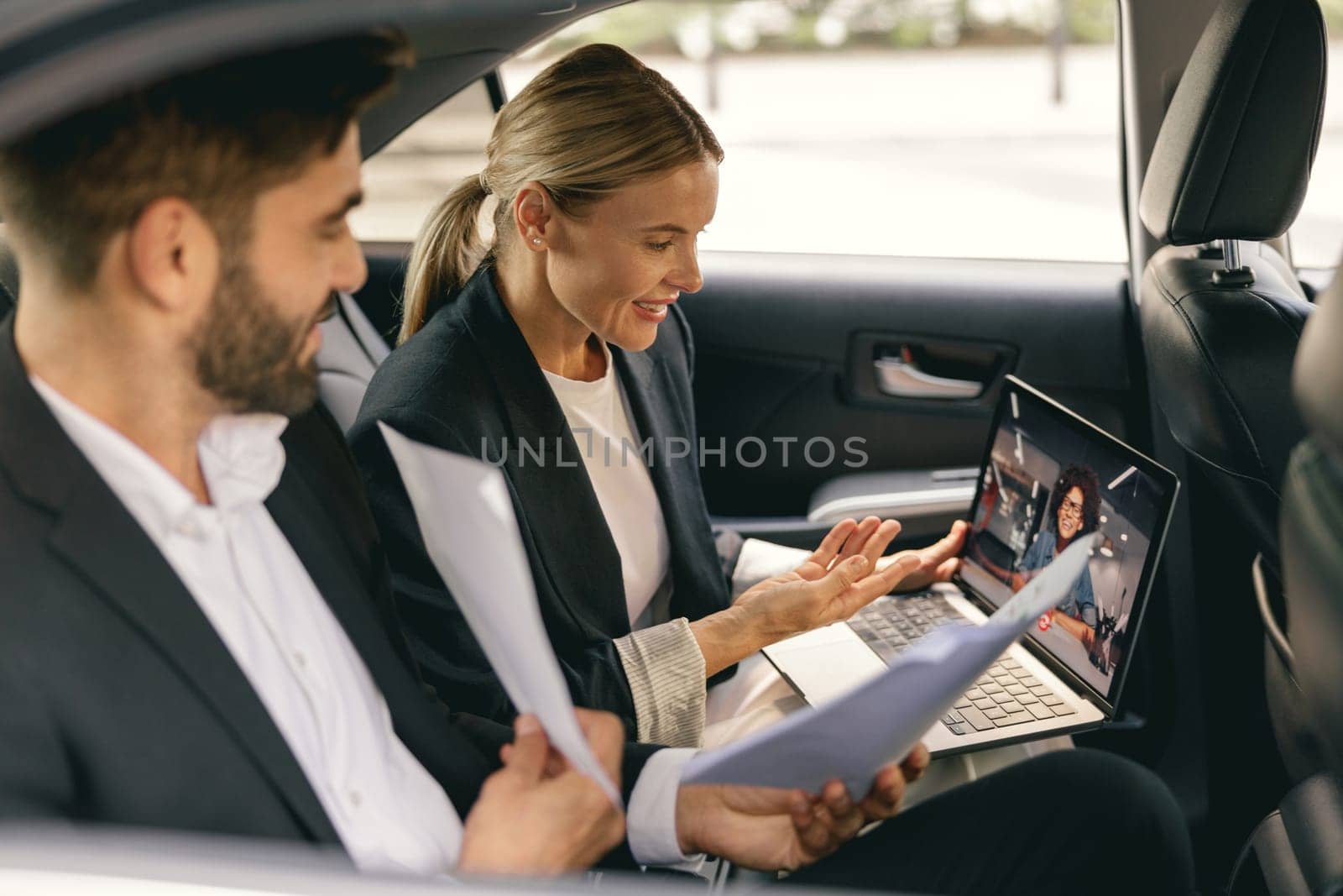 Successful business colleagues working together during video conference in back seat of car by Yaroslav_astakhov