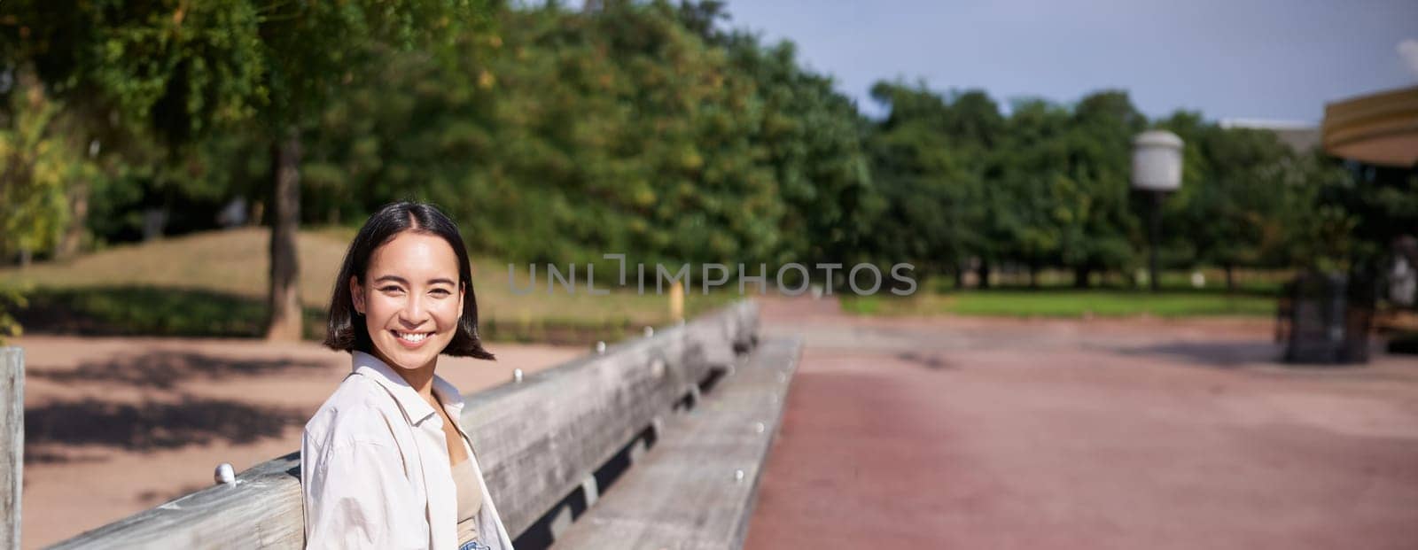 Portrait of young artist, asian girl drawing in digital tablet with graphic pen, sitting outdoors in park, getting inspiration.