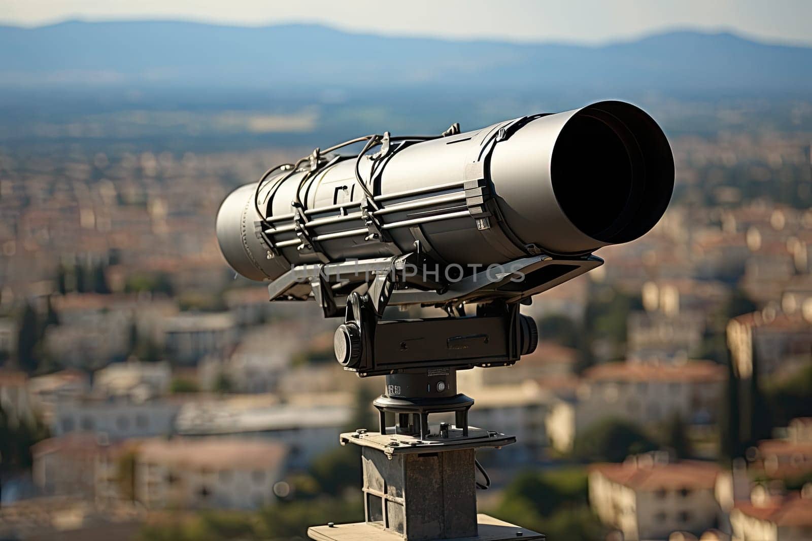 a city from the top of a building with a telescope on it's side and mountains in the background