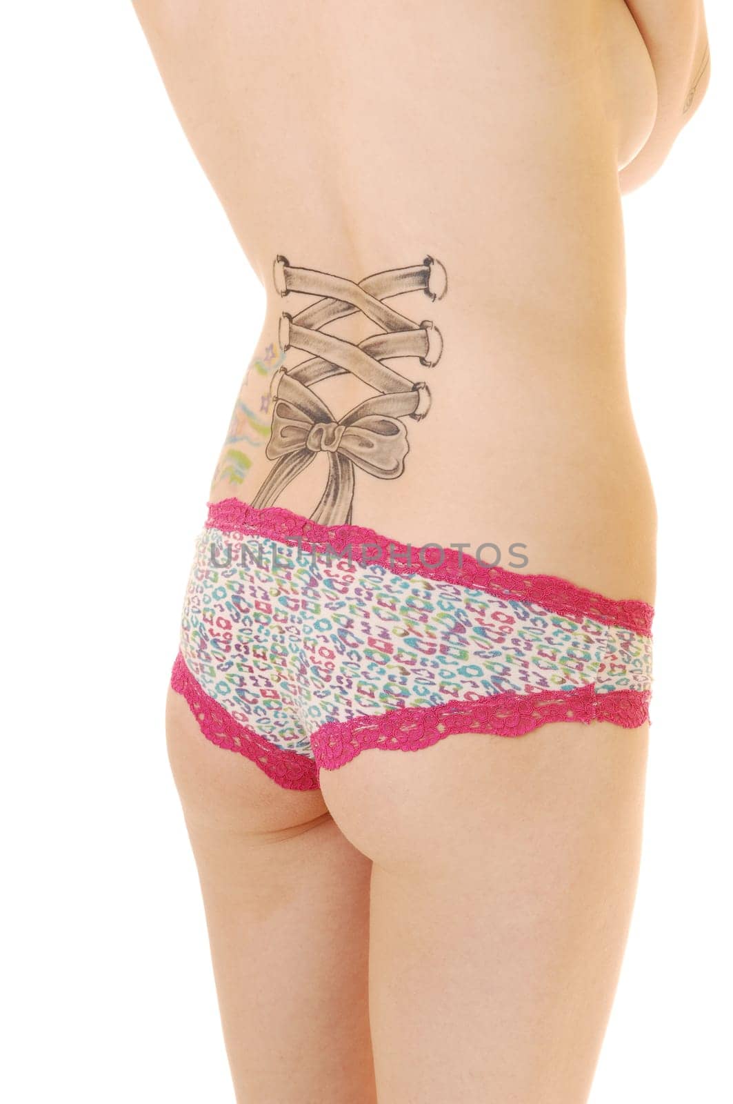 The back of a young woman with a tattoo, standing in the studio in panties from the back for white background.