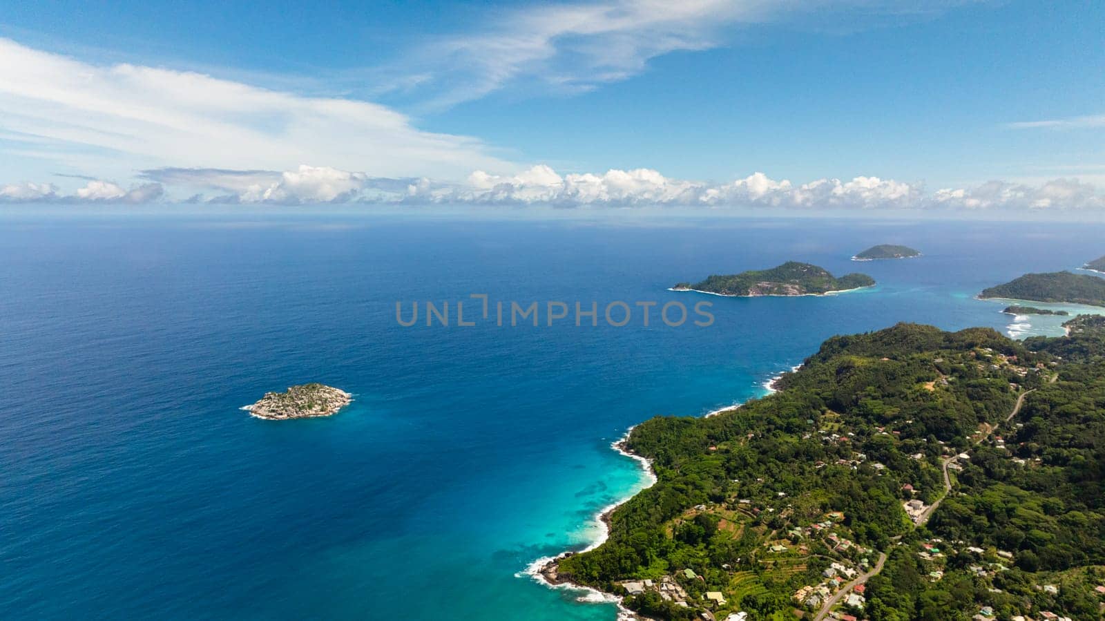 Expansive ocean view with distant islands and turquoise waters under a bright blue sky. Seychelles, Mahe.