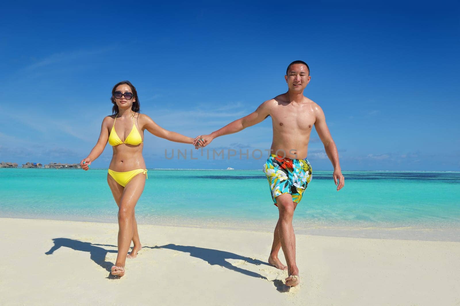 happy young asian couple enjoying summer and have on beautiful white sand beach