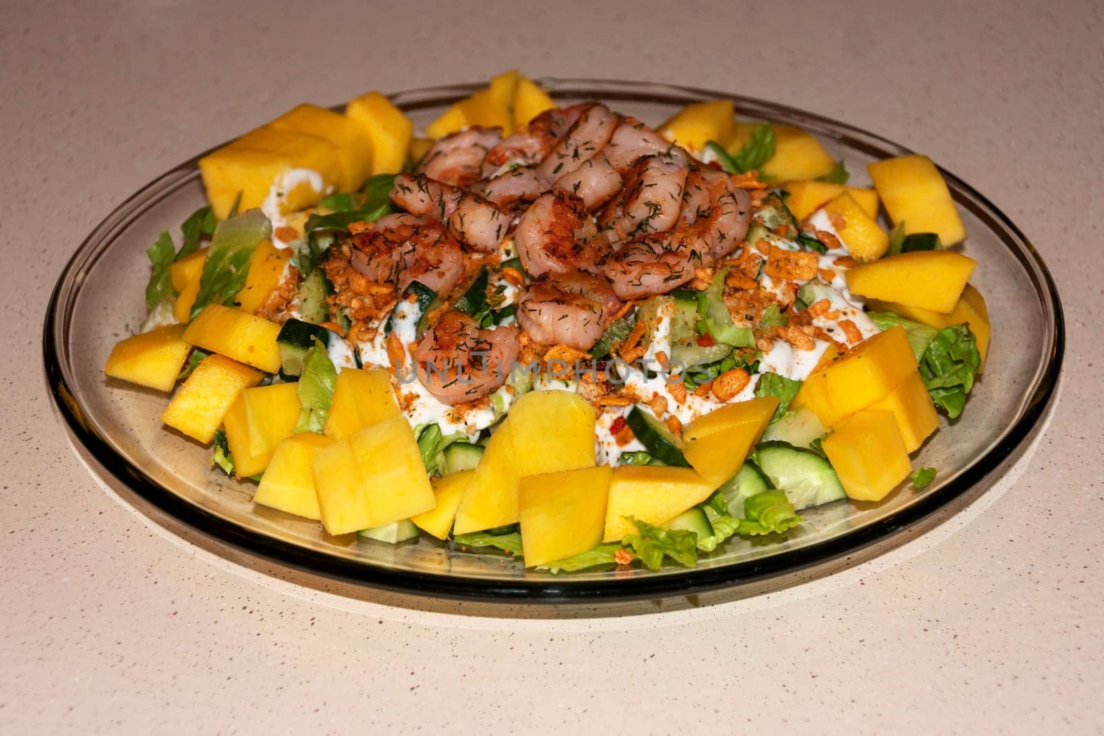 Glass plate with salad of greens, mango and shrimp