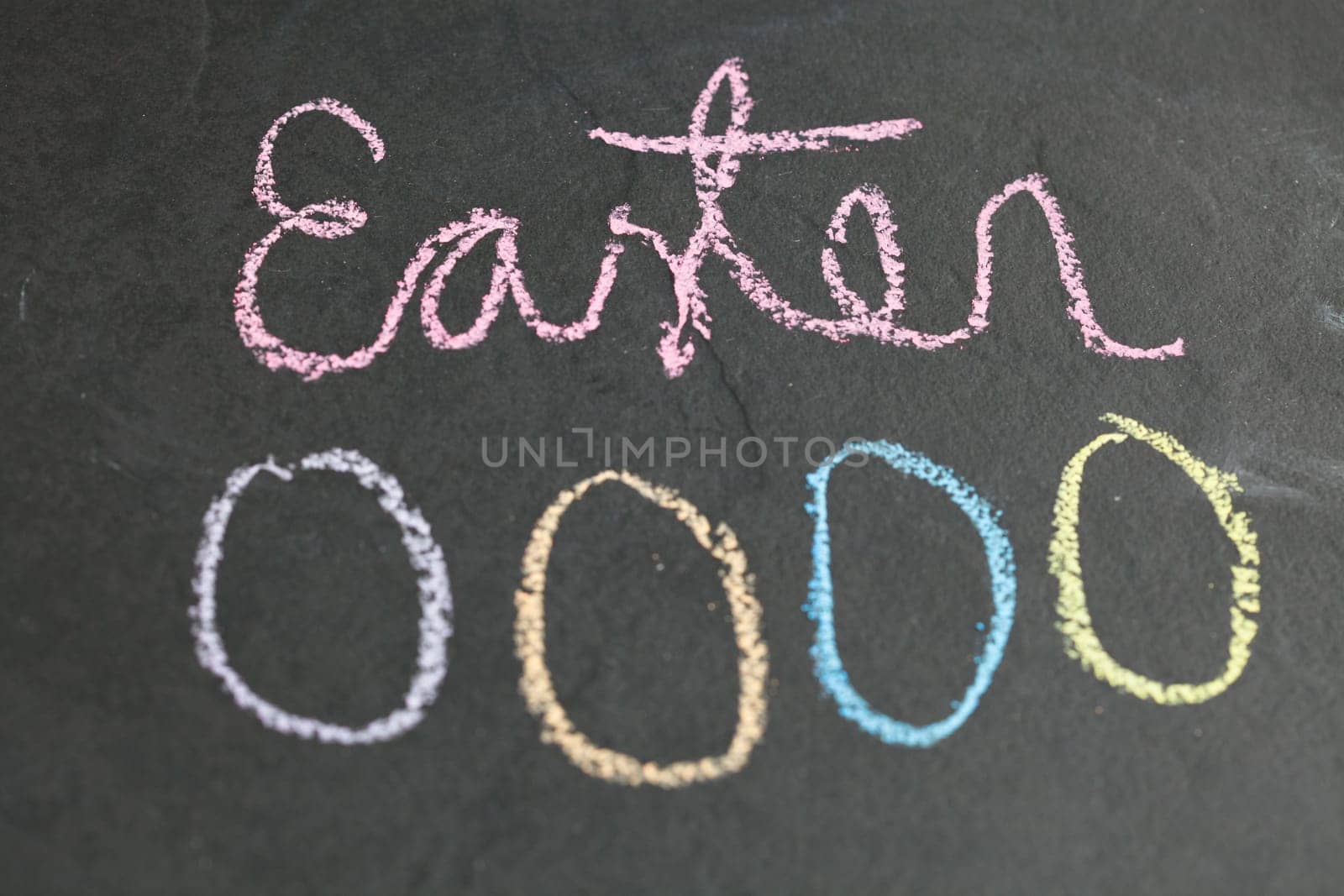 Closeup of four Easter egg shaped chalk drawings and text on dark background