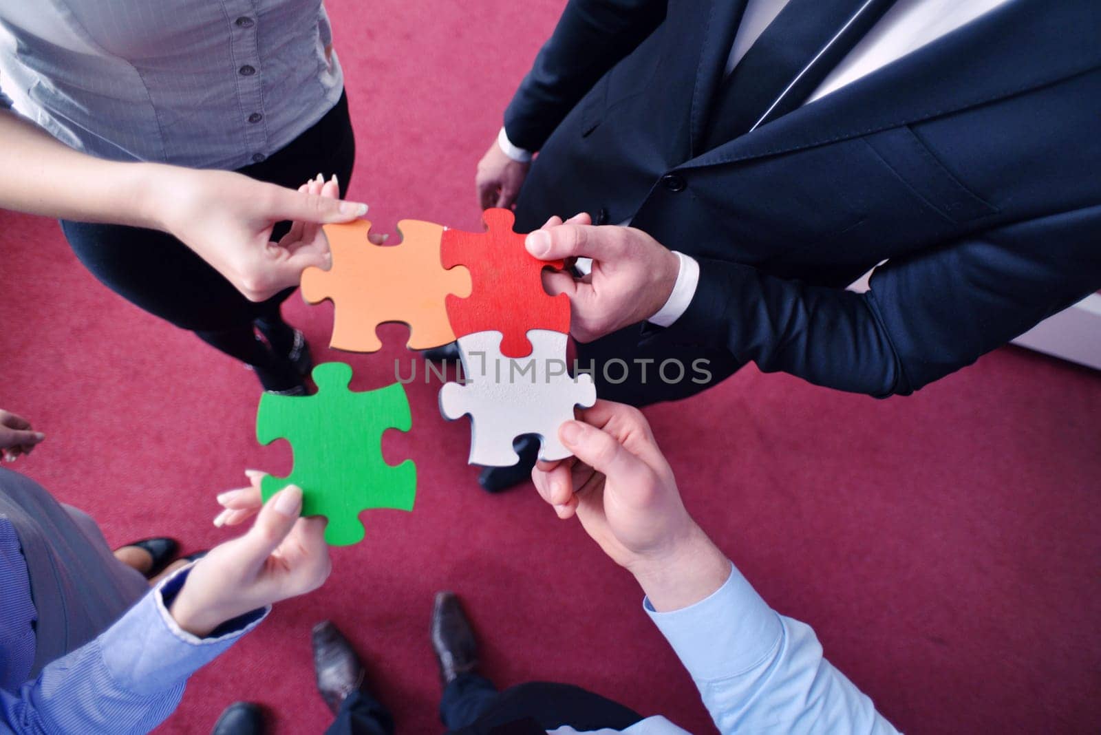 Group of business people assembling jigsaw puzzle and represent team support and help concept