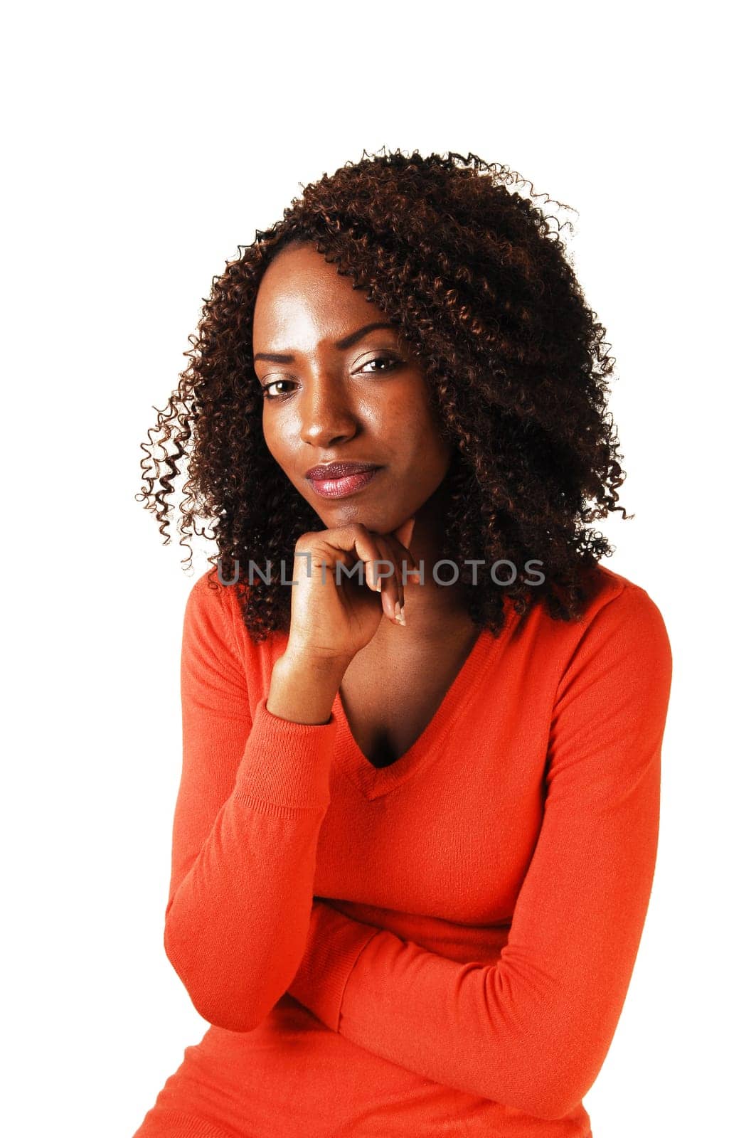 Closeup portrait of a lovely black teenager, looking into the camera, with one hand under her shin for white background.