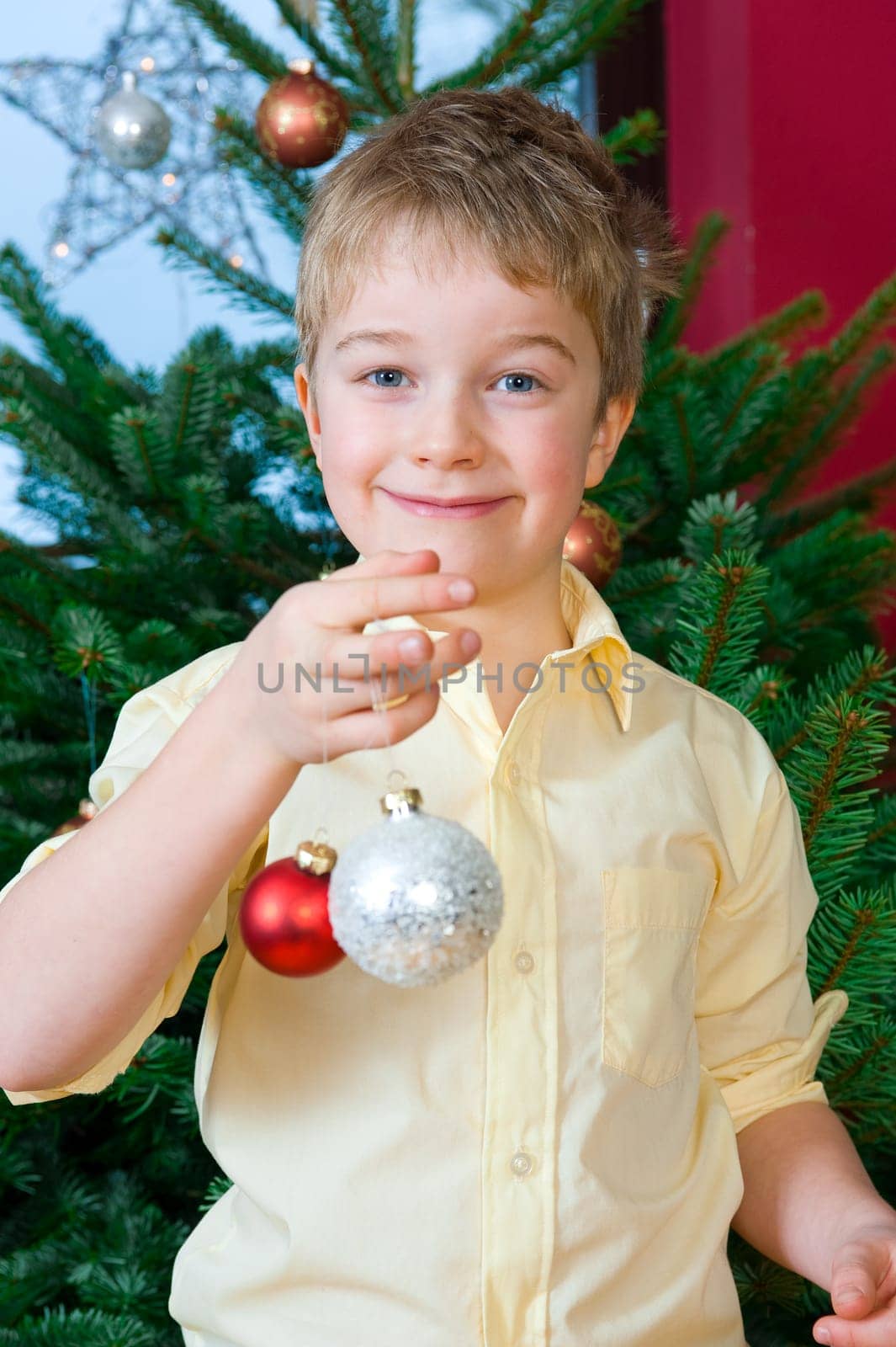 boy is decorating a christmas tree