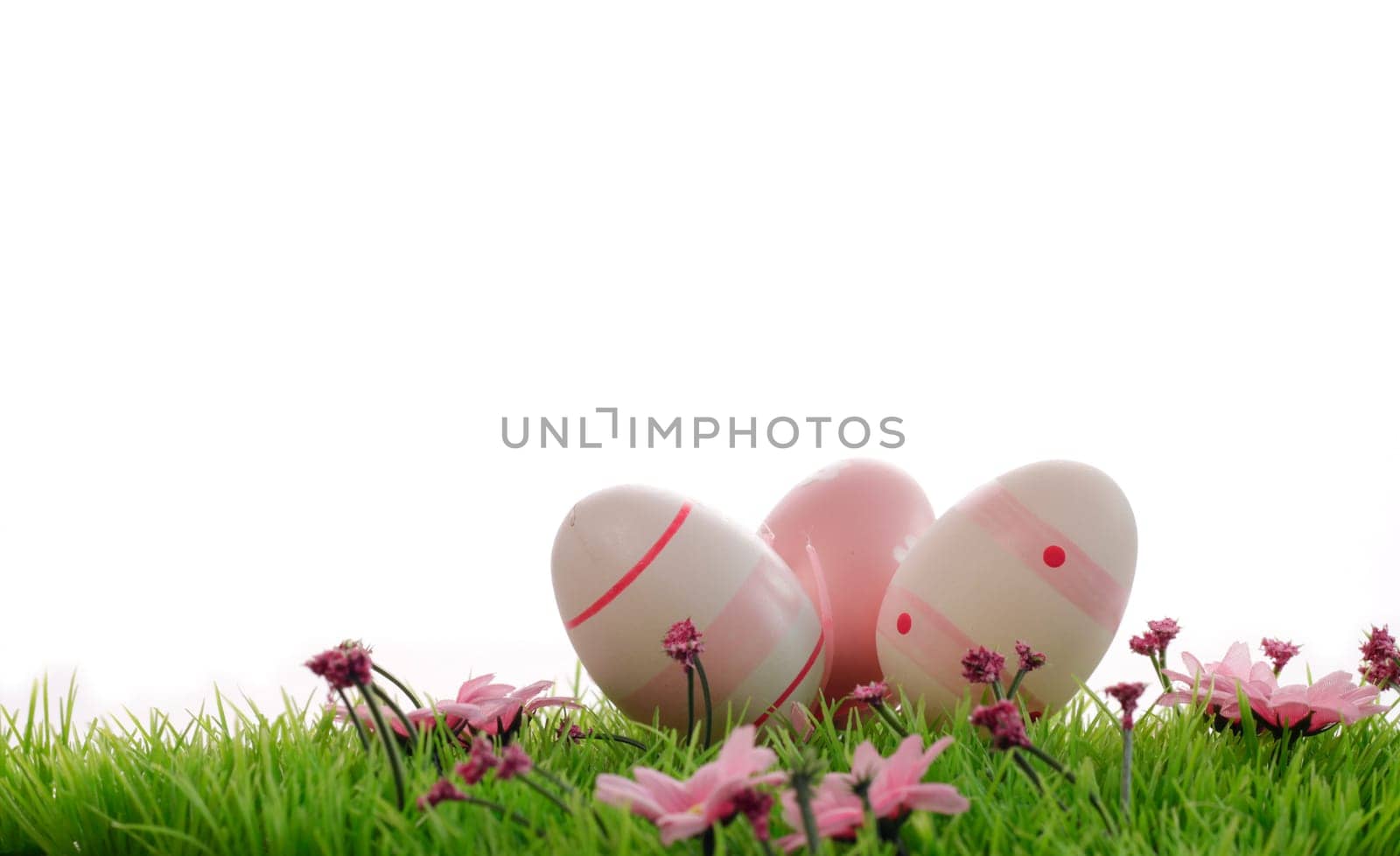 Three pink Easter eggs on a green meadow