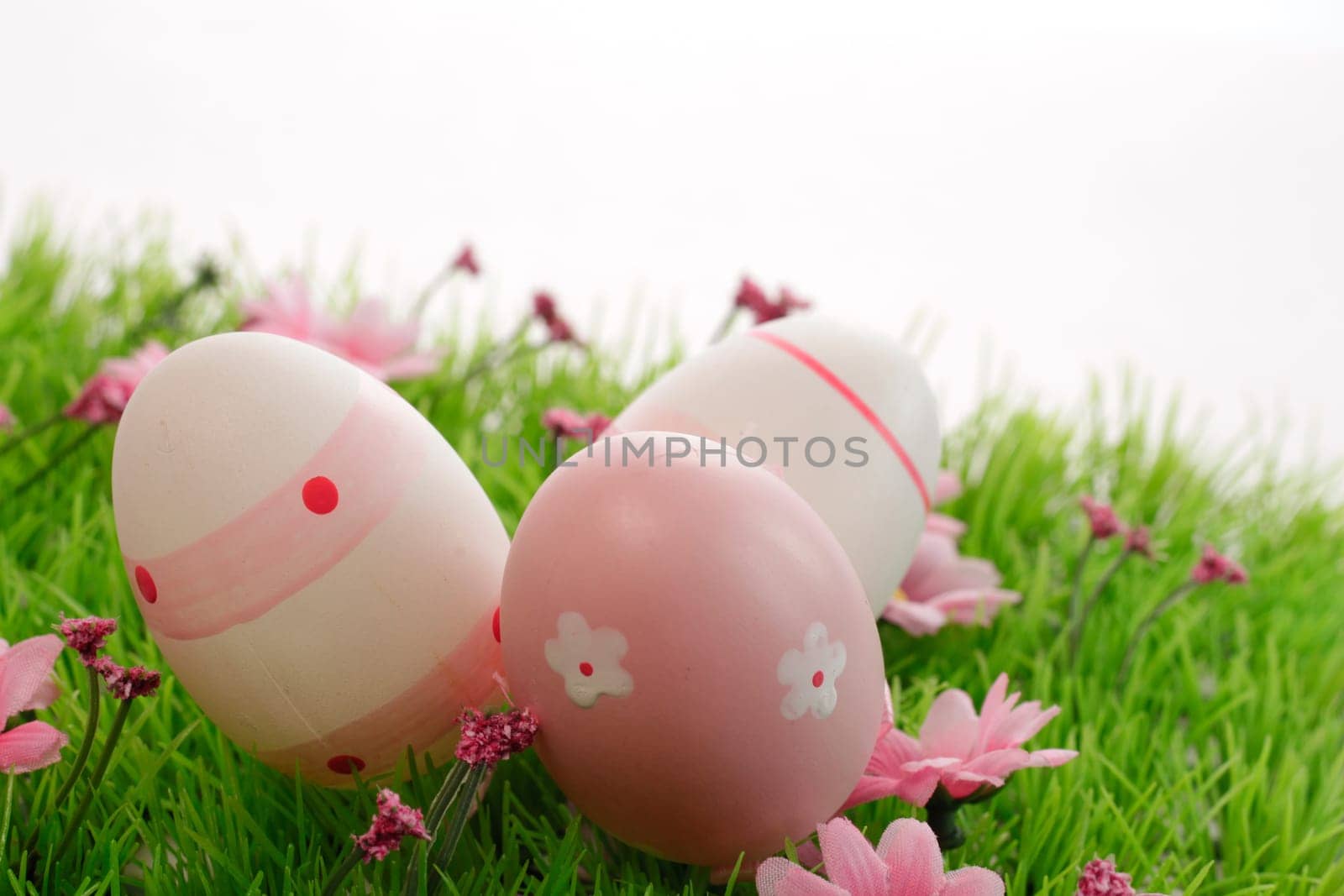 Three pink Easter eggs on a green meadow