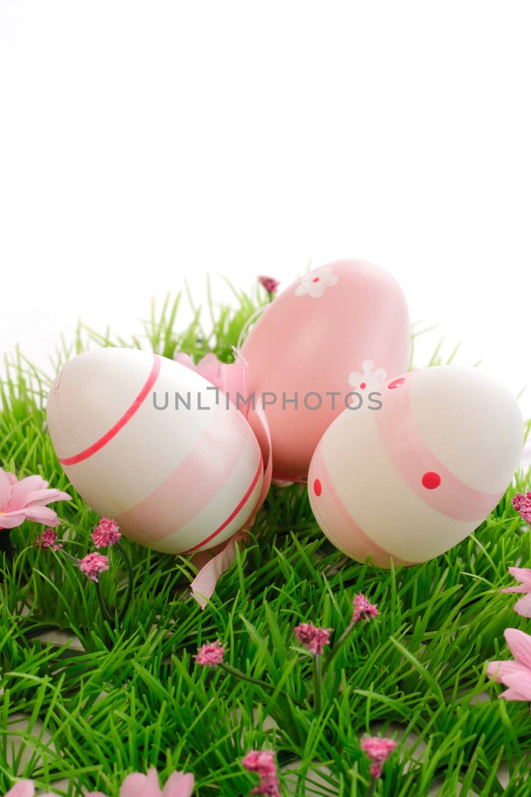 Three pink Easter eggs on a green meadow