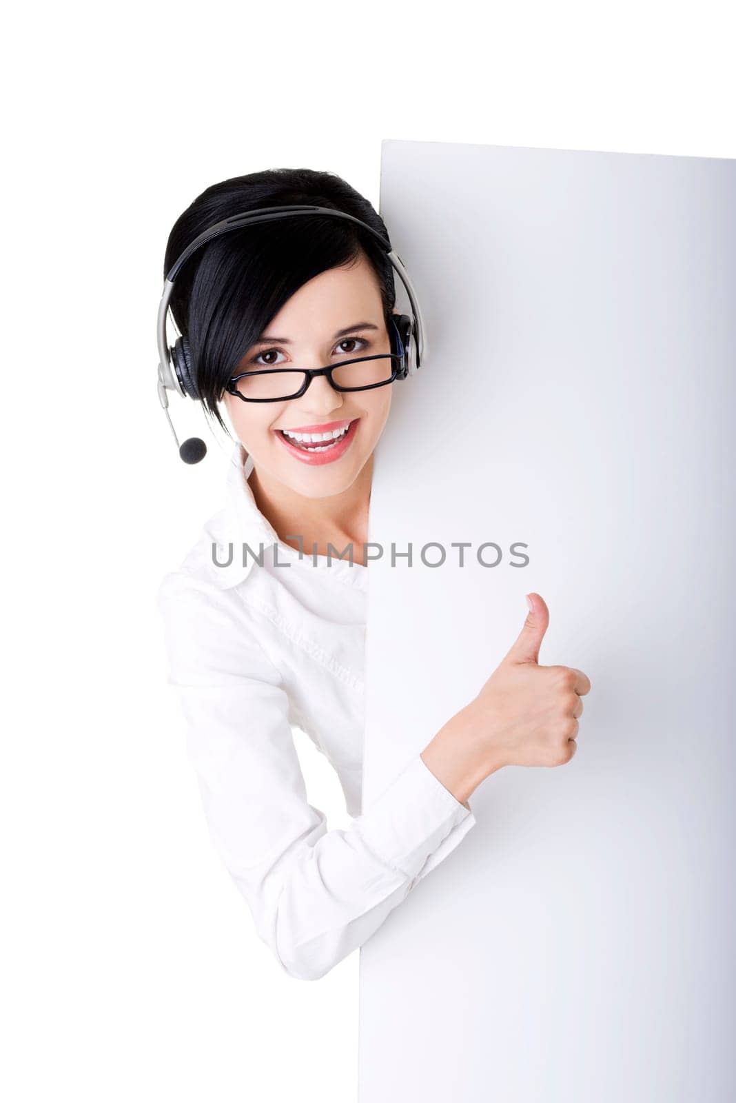 Pretty young call center worker wearing a headset and holding blank sign board