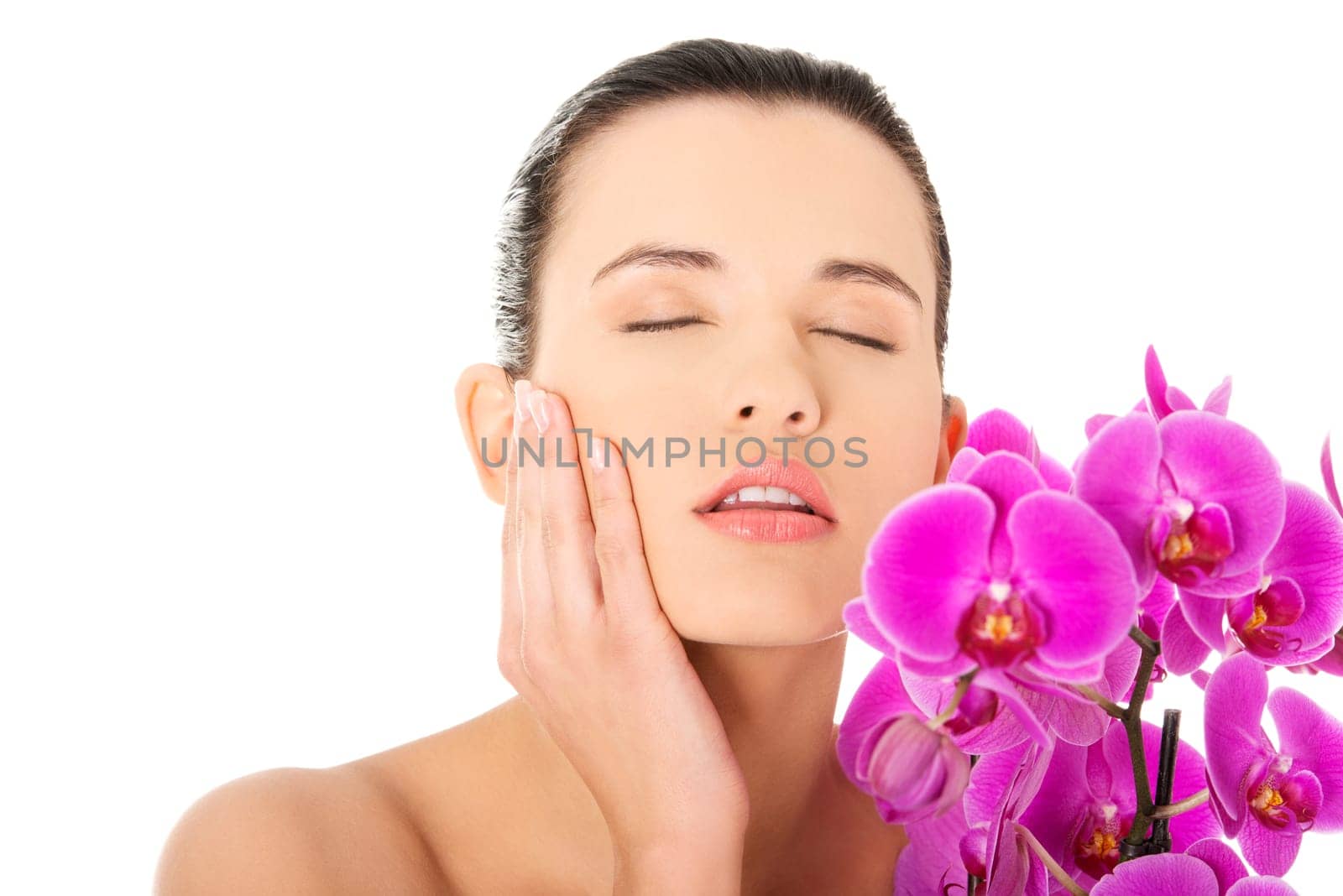 Portrait of beautiful young woman with health skin and with orchid flower