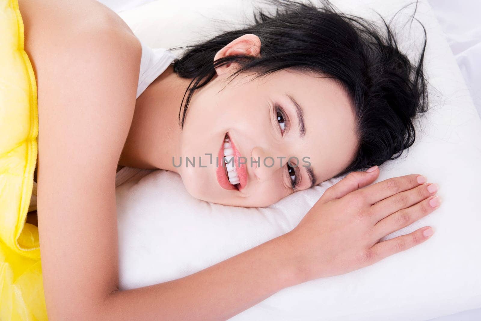 Happy sensual young woman lying in bed and smiling to camera