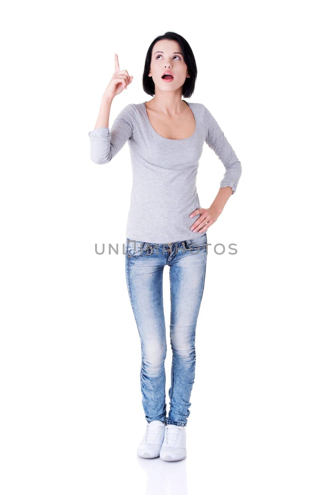Surprised woman with opened mouth pointing up on copy space. Isolated on white background.