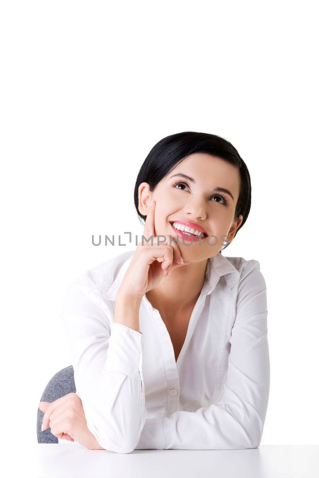 Young beautiful happy businesswoman behind the desk looking up on copy space, isolated