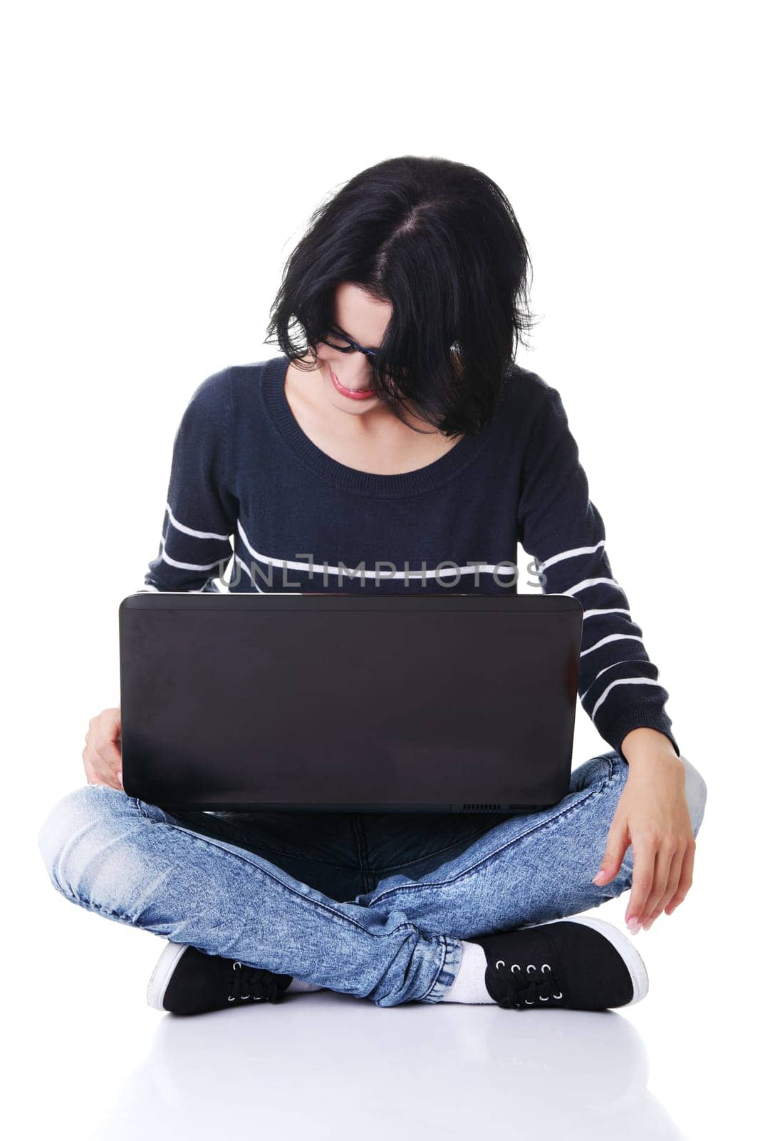 A young thoughtful woman with a laptop sitting isolated on white background