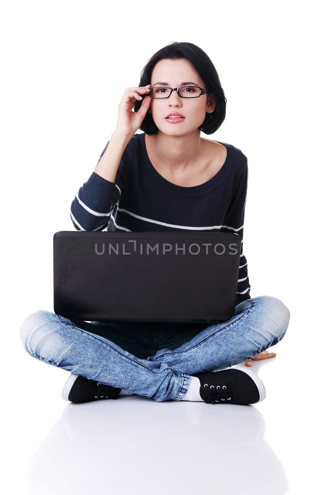 A young thoughtful woman with a laptop sitting isolated on white background
