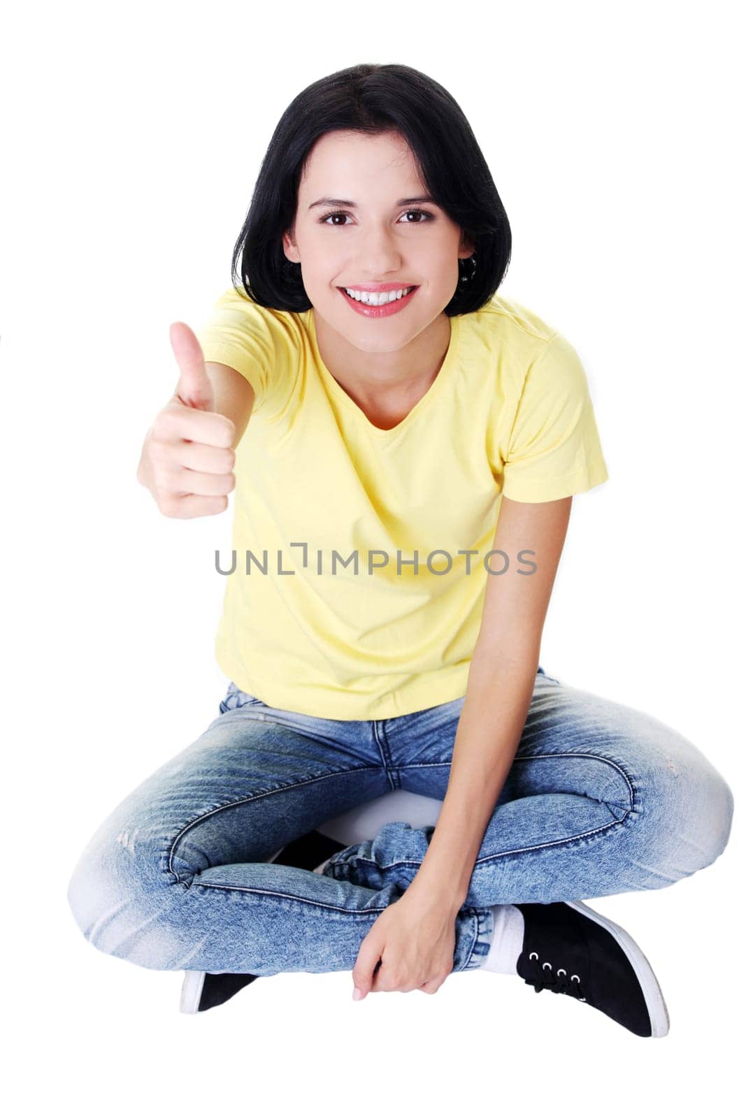 Young woman sitting on floor and gesturing OK , isolated on white