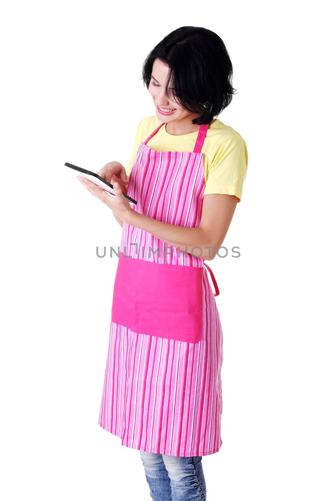 Young woman in pink apron using tablet computer, isolated