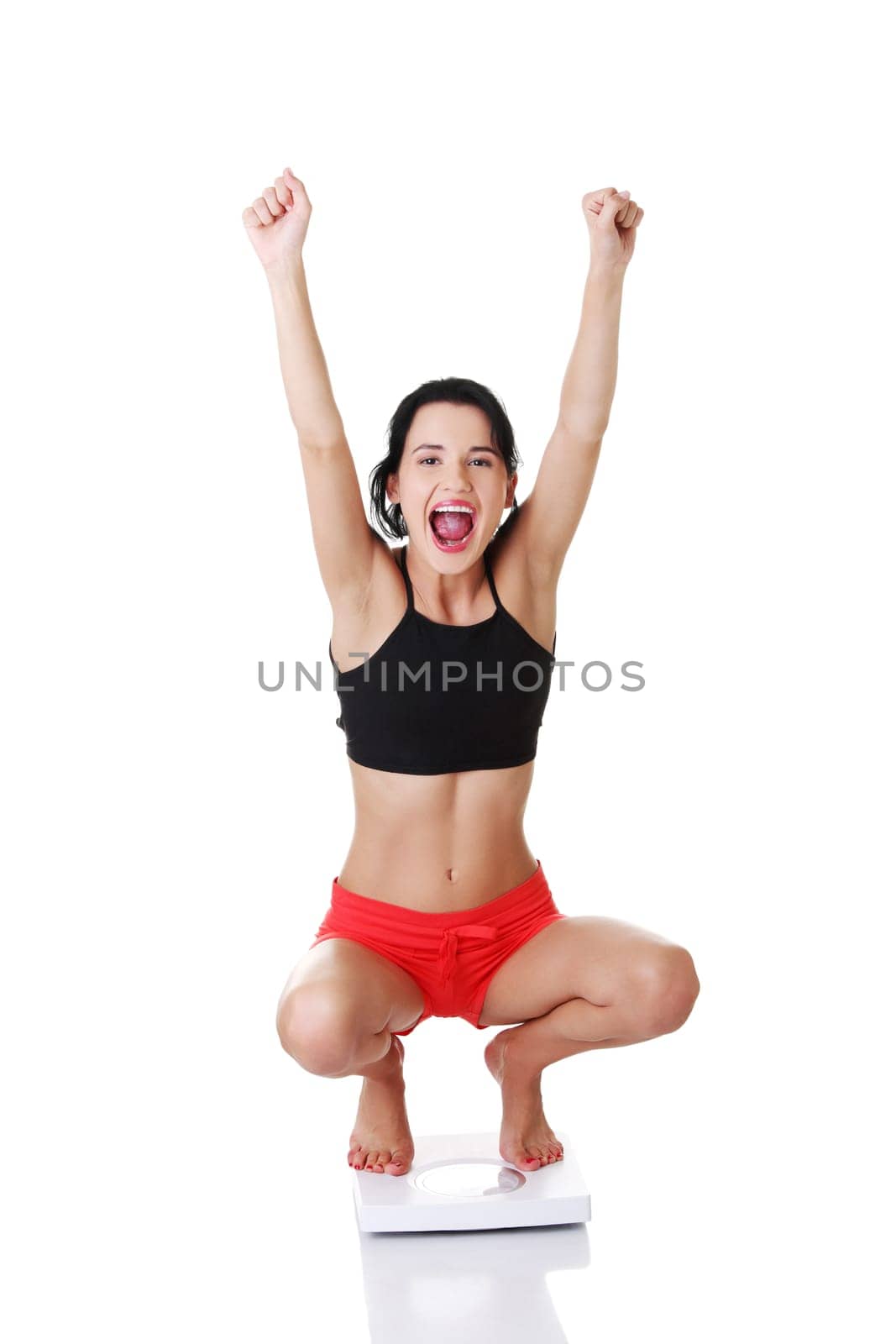 Portrait of a happy woman on scales. Weight-loss concept.