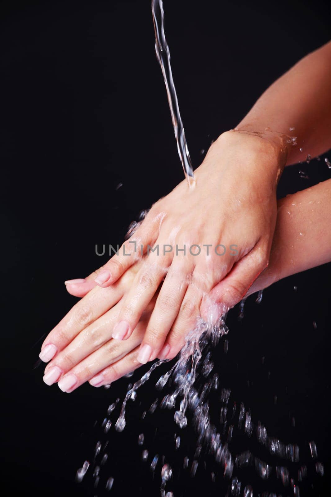 Water falling on female hands, over black background