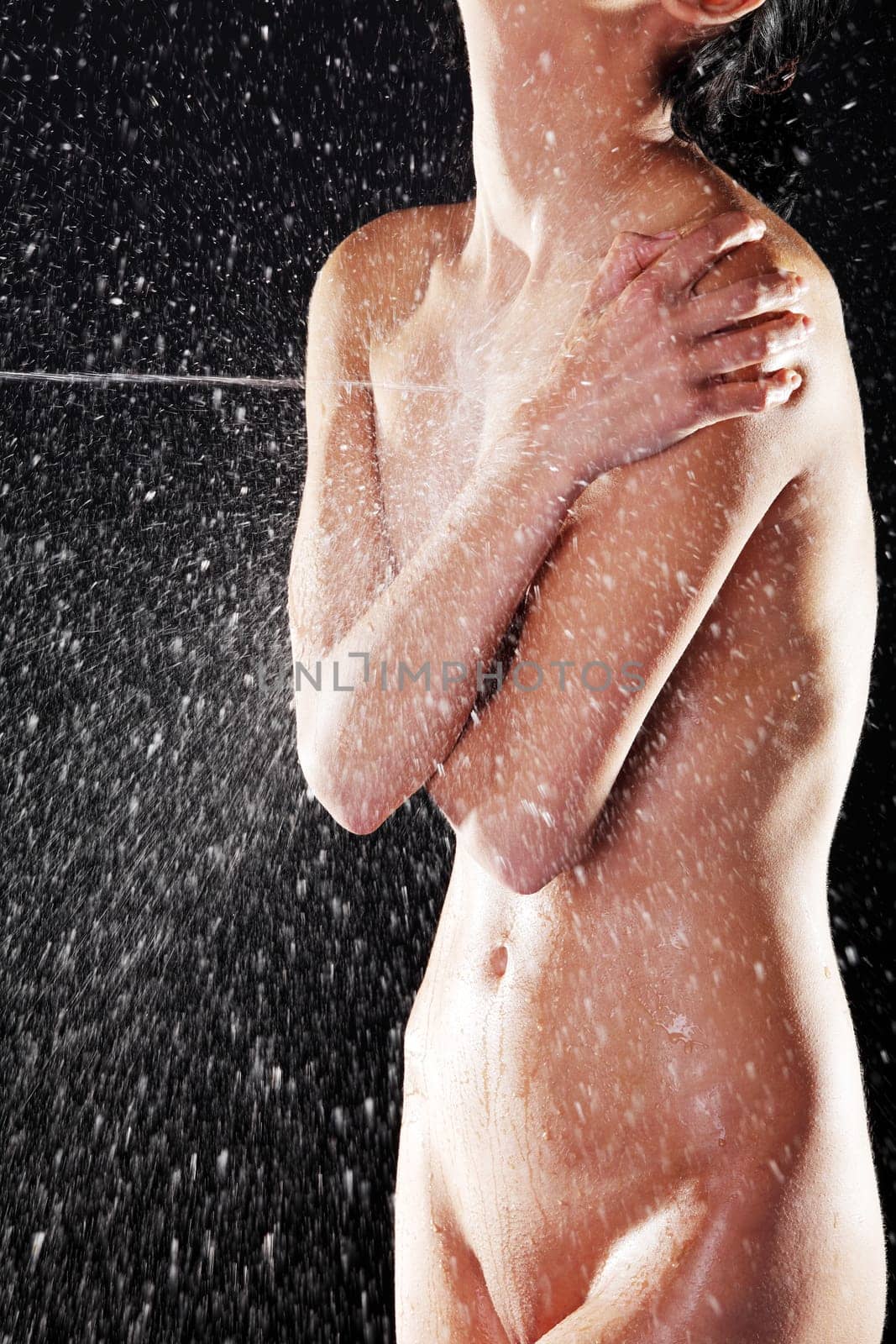 Water splashing on fit nude female body, over black background