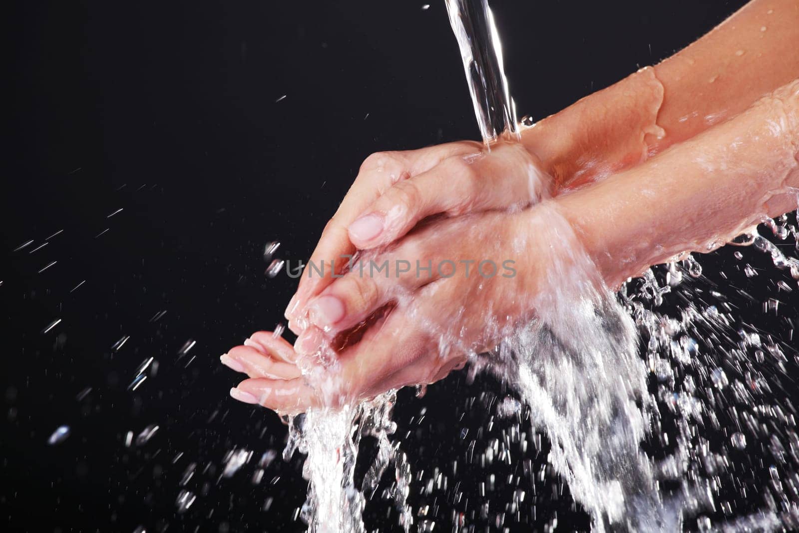 Water falling on female hands, over black background