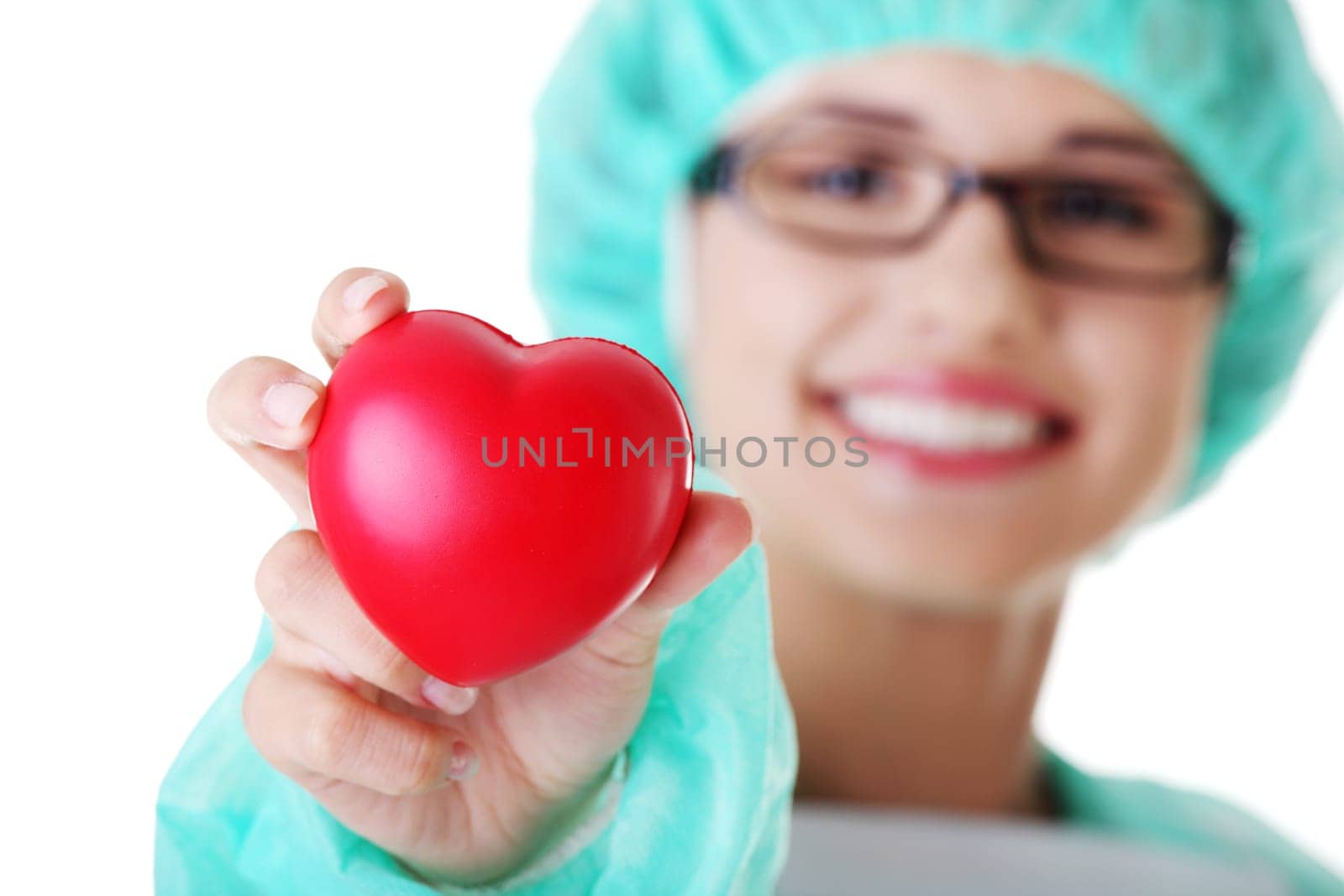 Smiling female doctor or nurse in surgical clothes holding red heart