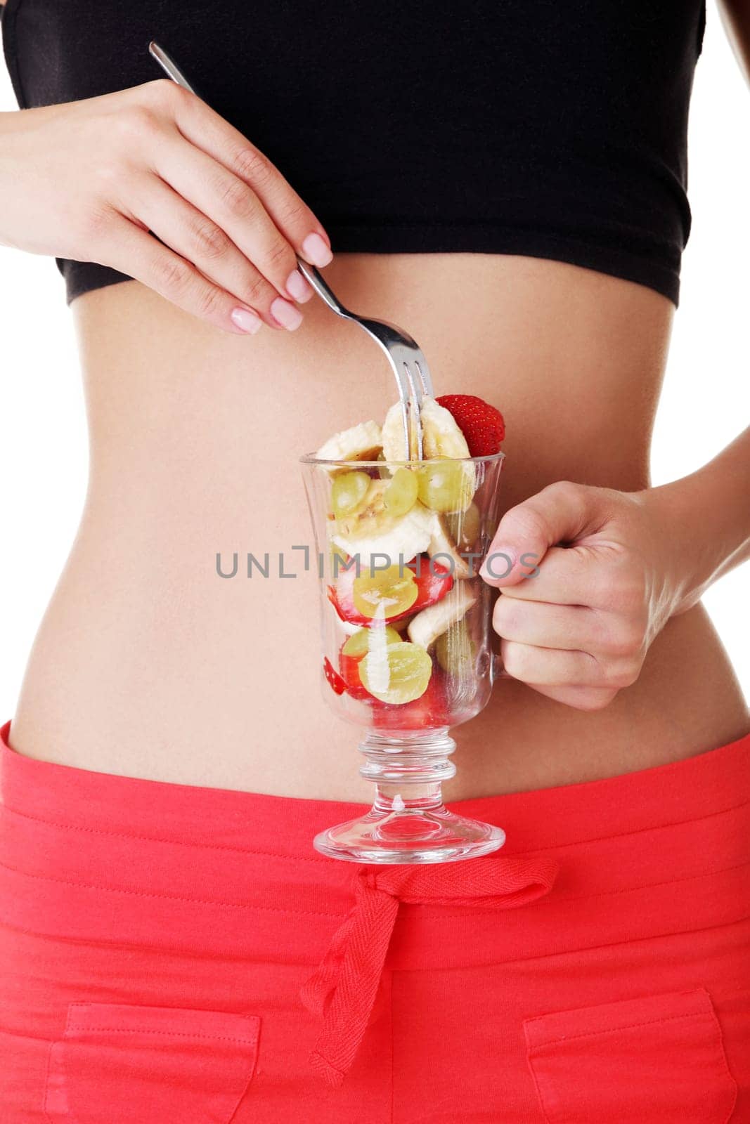 Close up of pretty fit woman belly and fruit salad