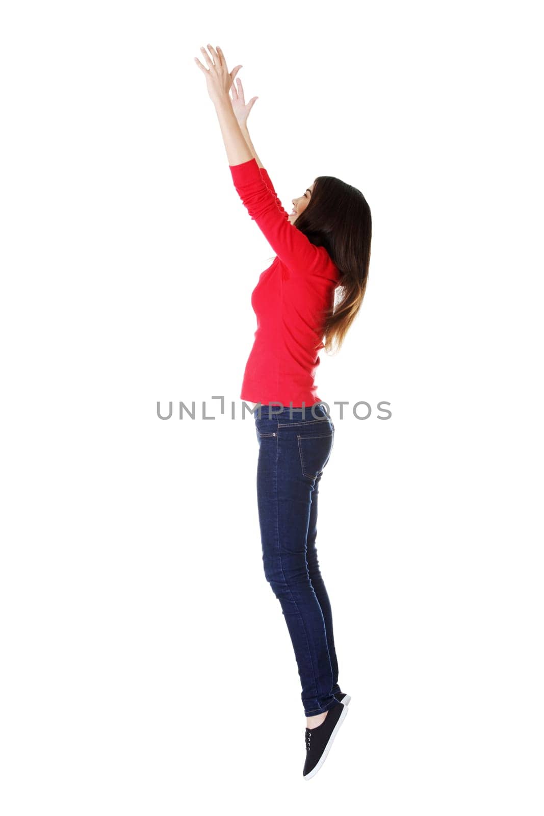 Teen girl jumping in air trying to catch something. Isolate don white.