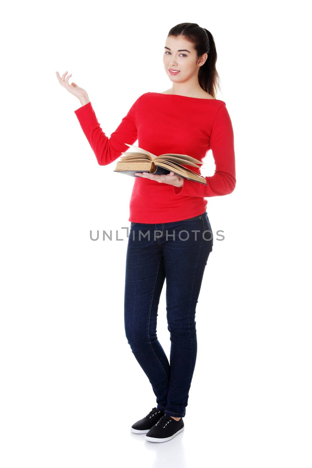 Happy young woman (student or teacher) with book in hand showing on copy space. Isolated on white.