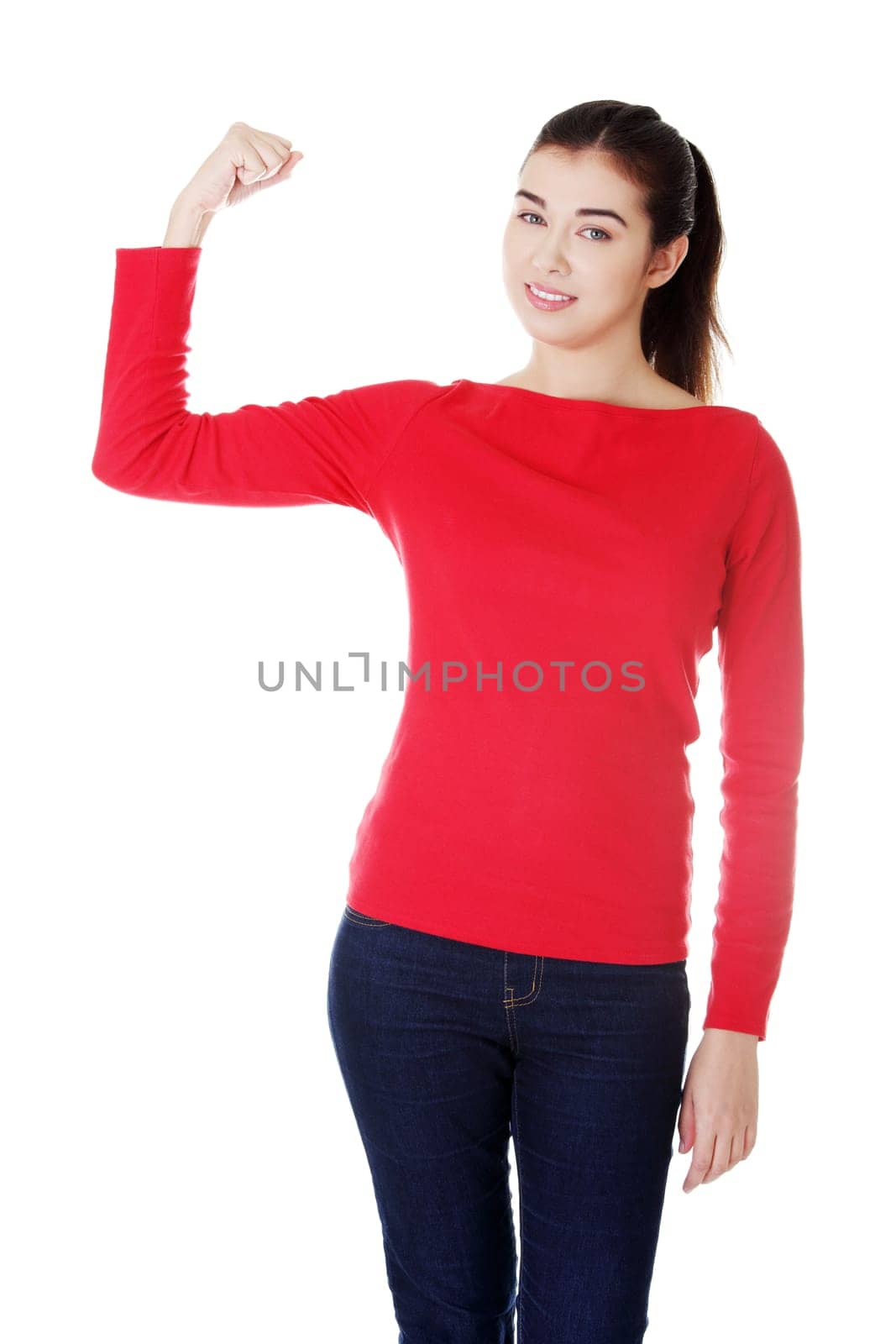 Young woman shows her biceps. She wears glasses and informal dress. Isolated on the white background.