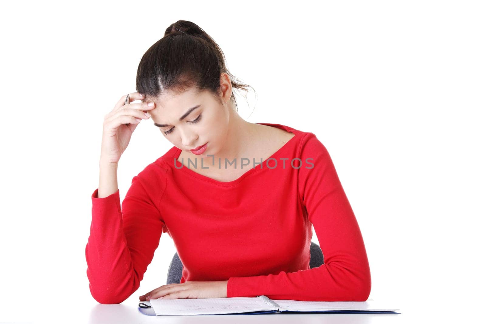 Pretty young student woman in casual clothes sitting at the desk and thinking, isolated on white