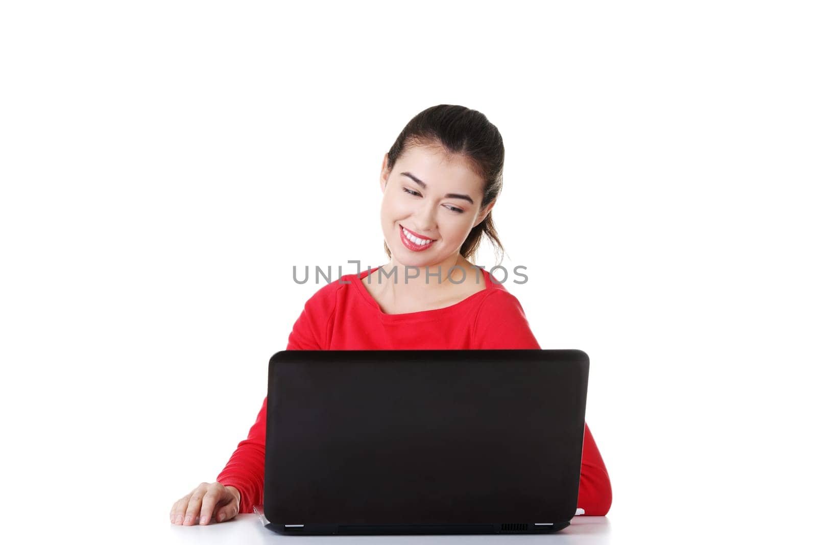 Happy young woman using her laptop at the desk, isolated on white.