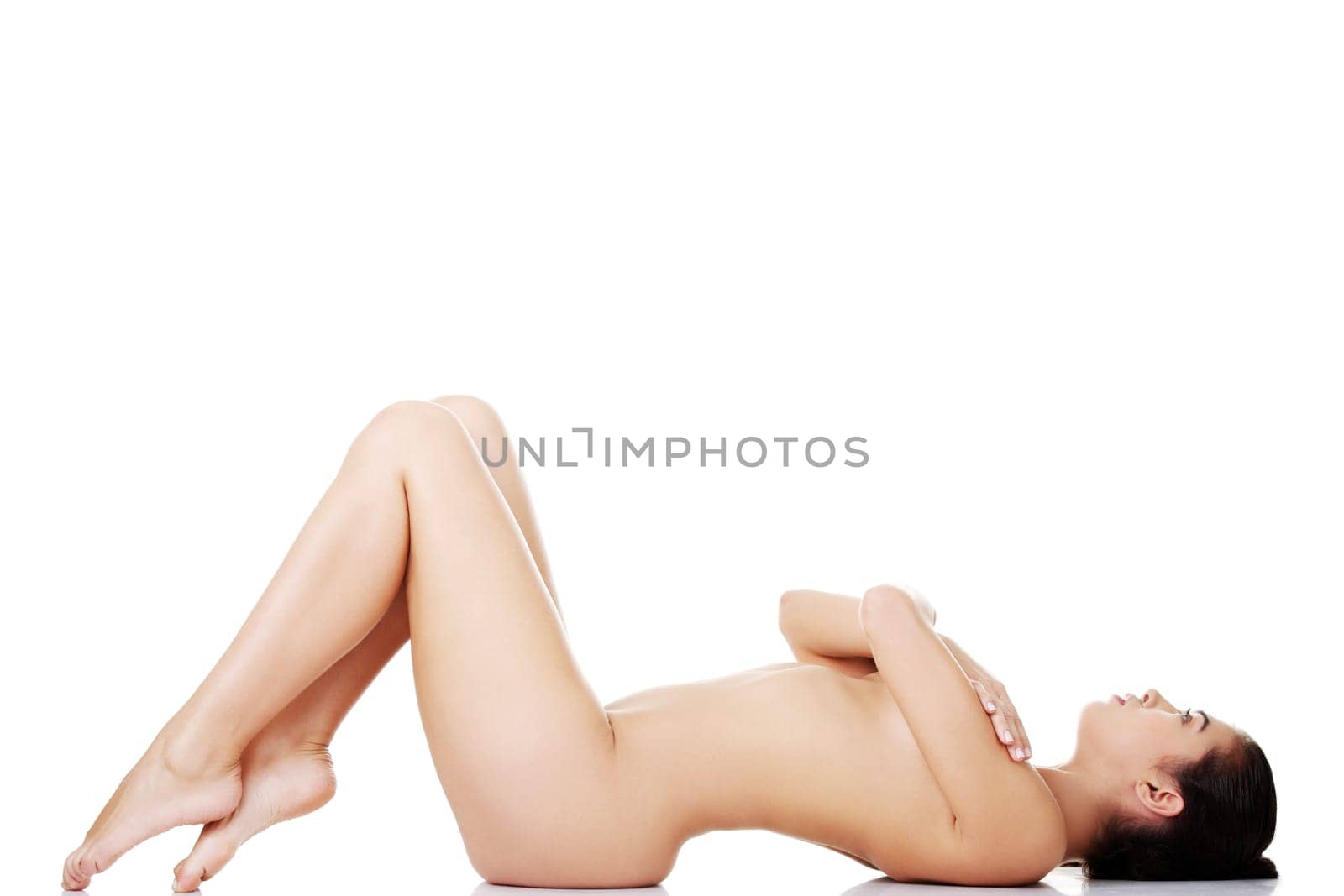 Sexy fit naked woman with healthy clean skin lying down, isolated on white
