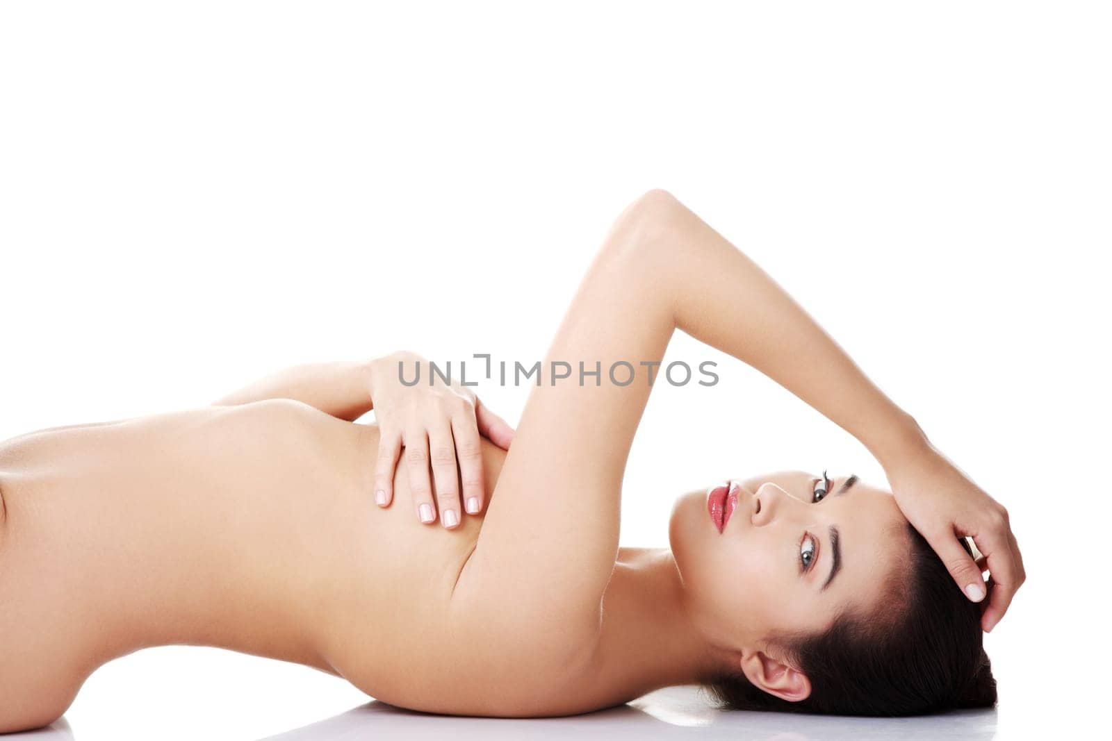 Sexy fit naked woman with healthy clean skin lying down, isolated on white