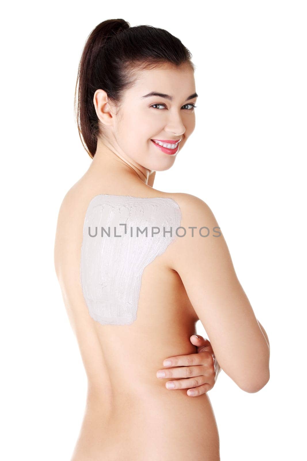 Charming nude woman enjoying a mud skin treatment on her back. Isolated on white