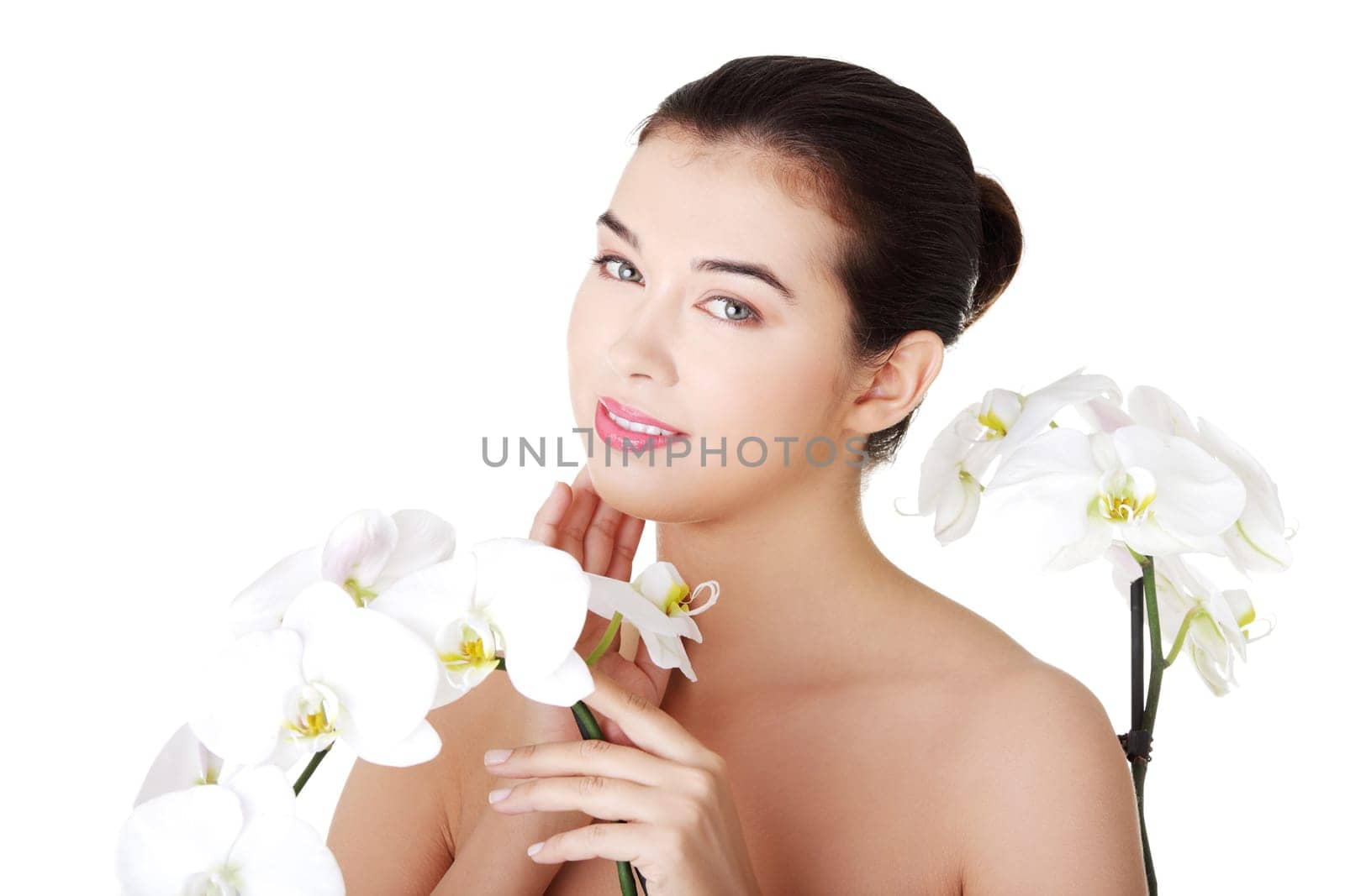 Portrait of beautiful young woman with health skin and with orchid flower