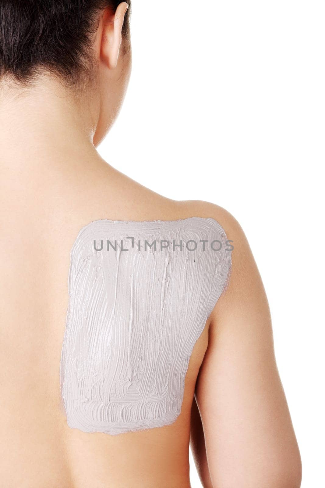 Charming nude woman enjoying a mud skin treatment on her back. Isolated on white