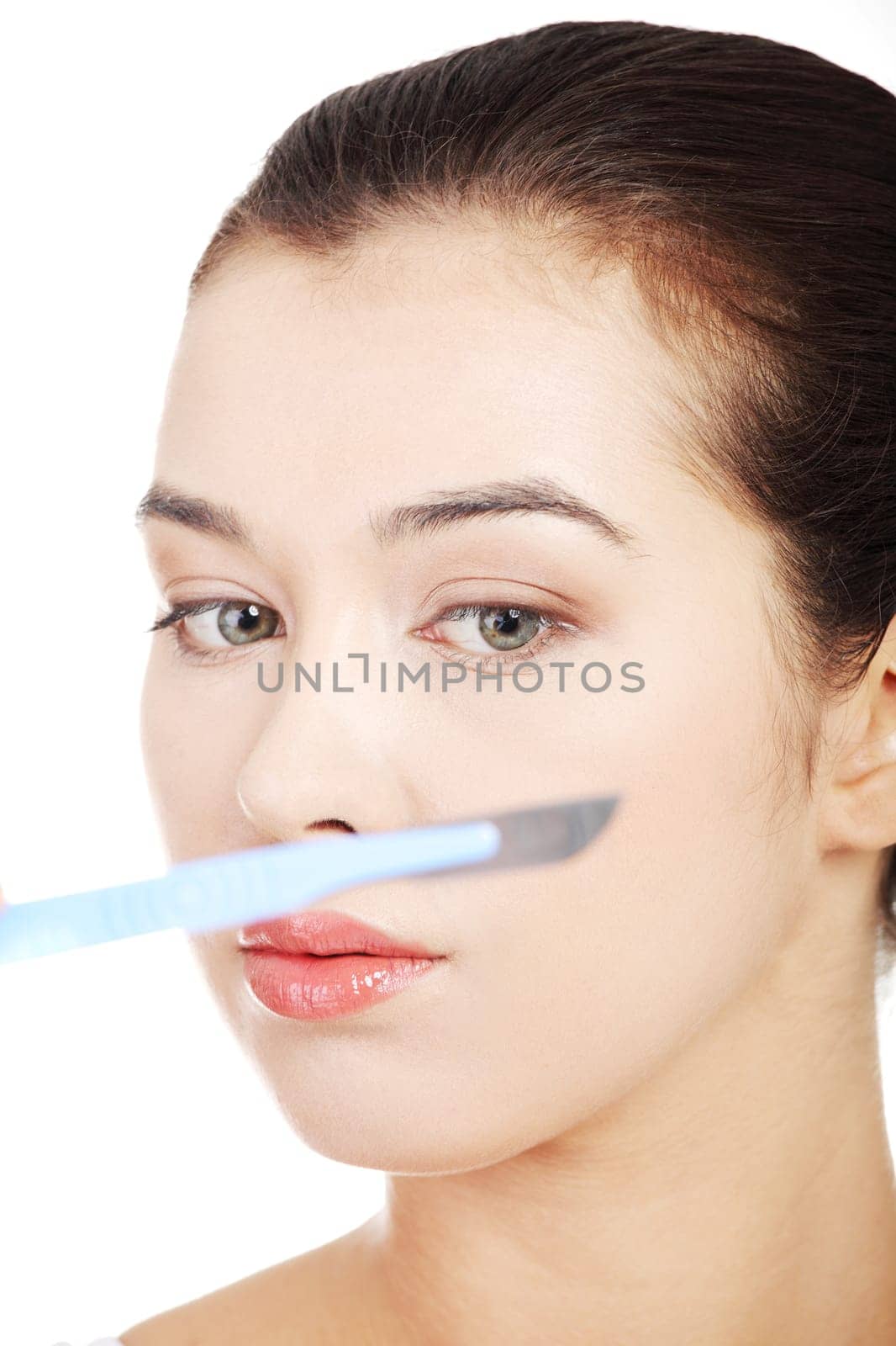 Cosmetic surgery concept. Female face in background of scalpel.