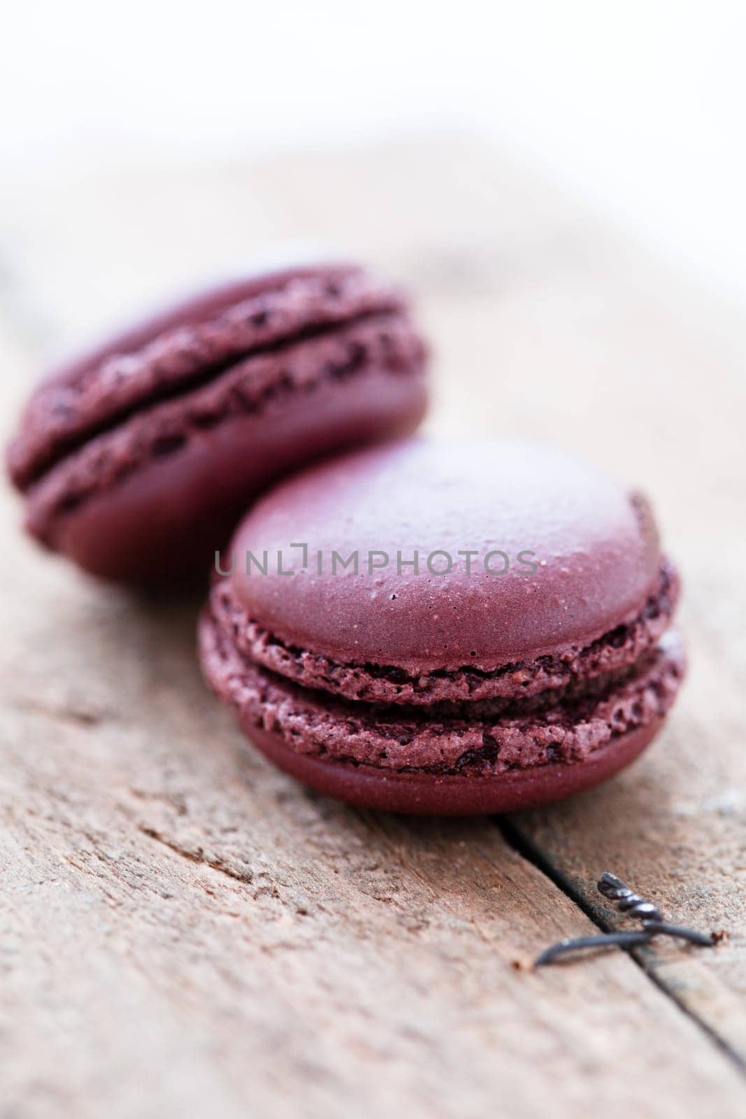 Closeup of two chocolate macaroons on wooden table