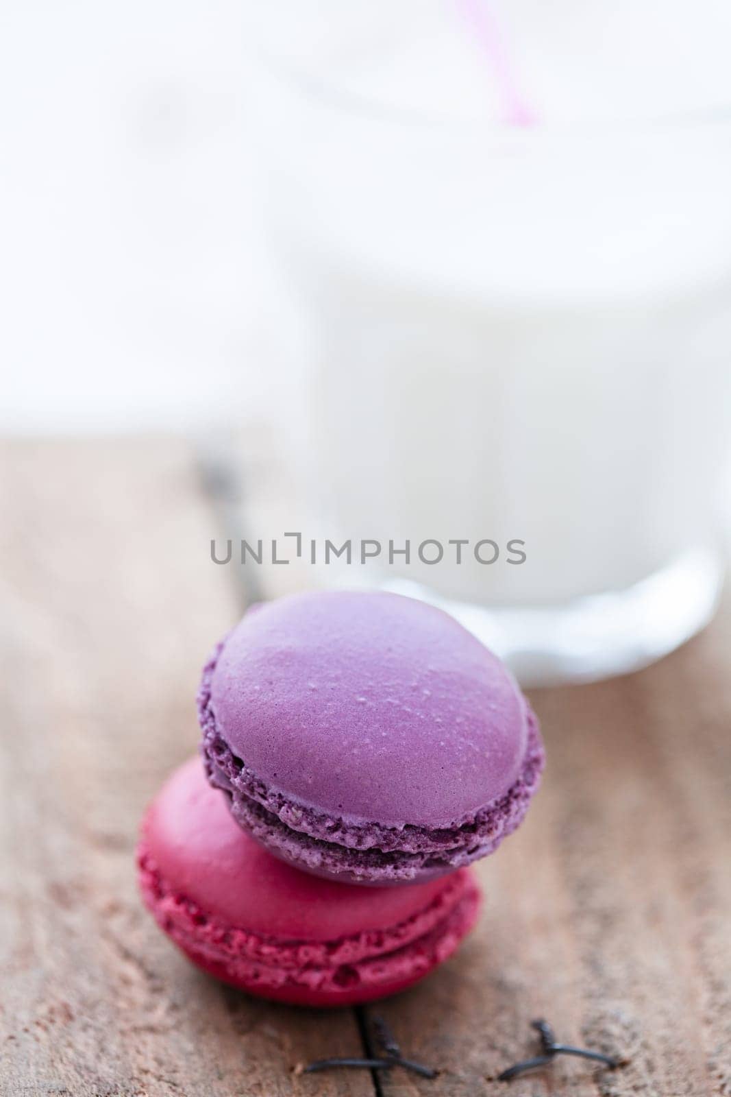 Closeup of two macaroons and glass milk on wooden table