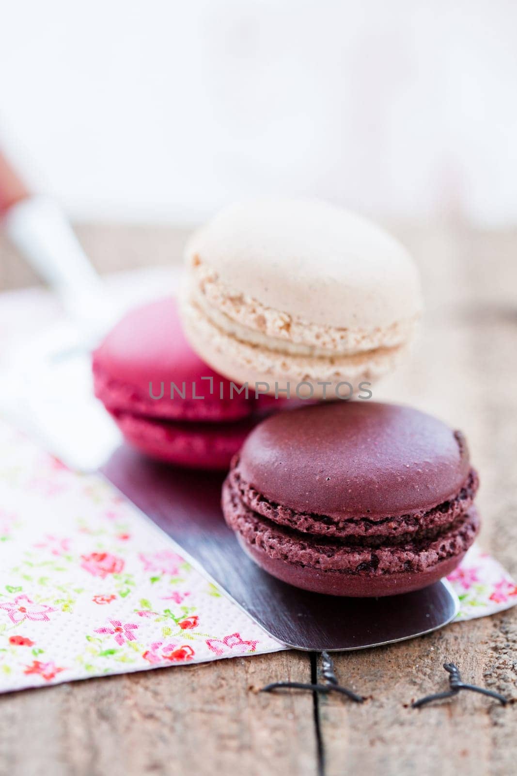 Closeup of three different flavoured macaroons on cake server on wooden table