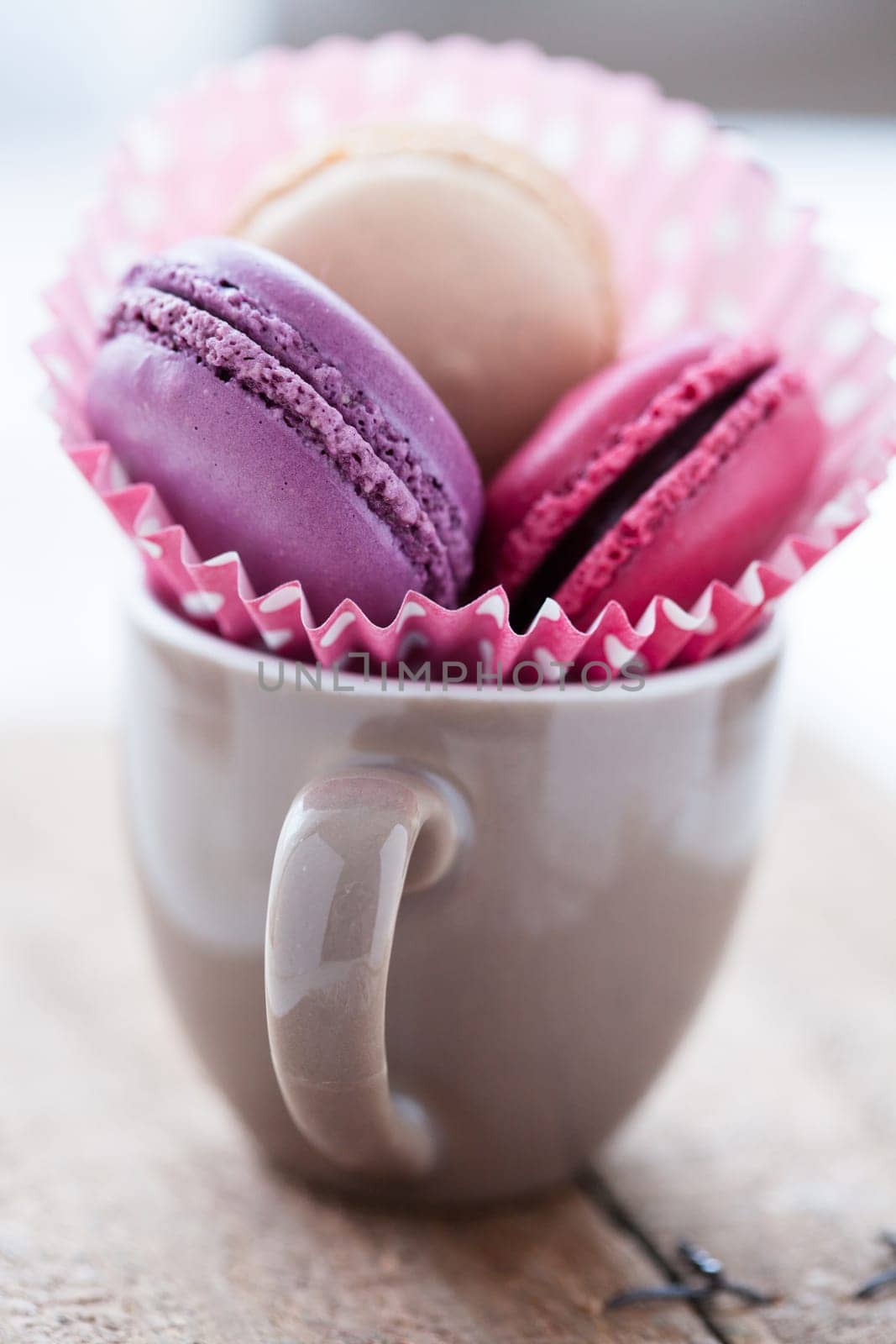 Closeup of three different flavoured macaroons in cup on wooden table