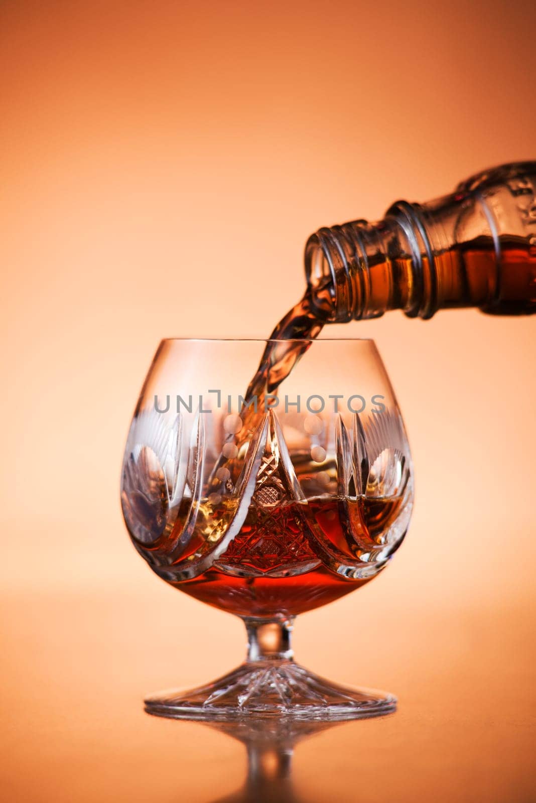 Close up of pouring cognac into glass