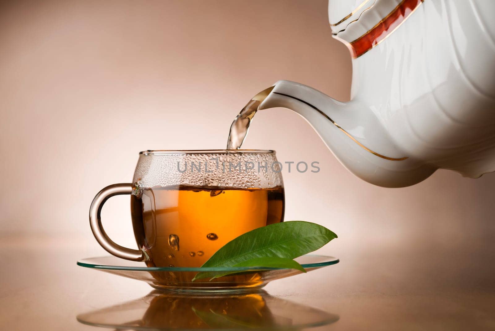 Hot green tea pouring in to cup close up