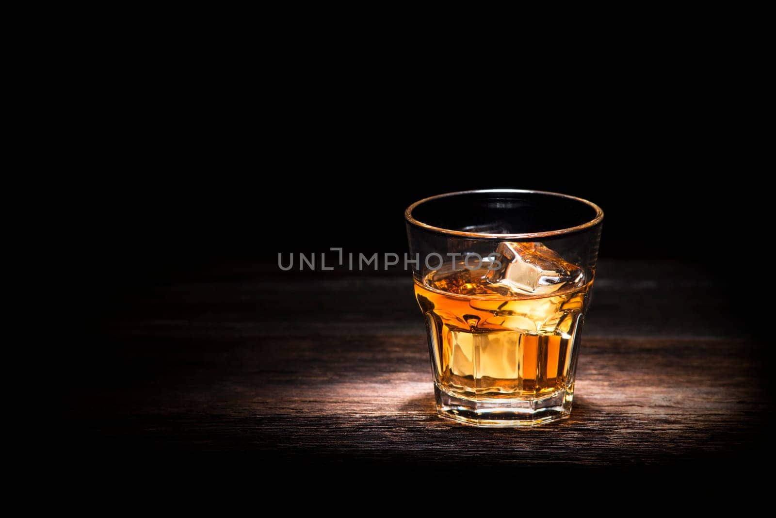 Glass of whiskey on wooden background close up