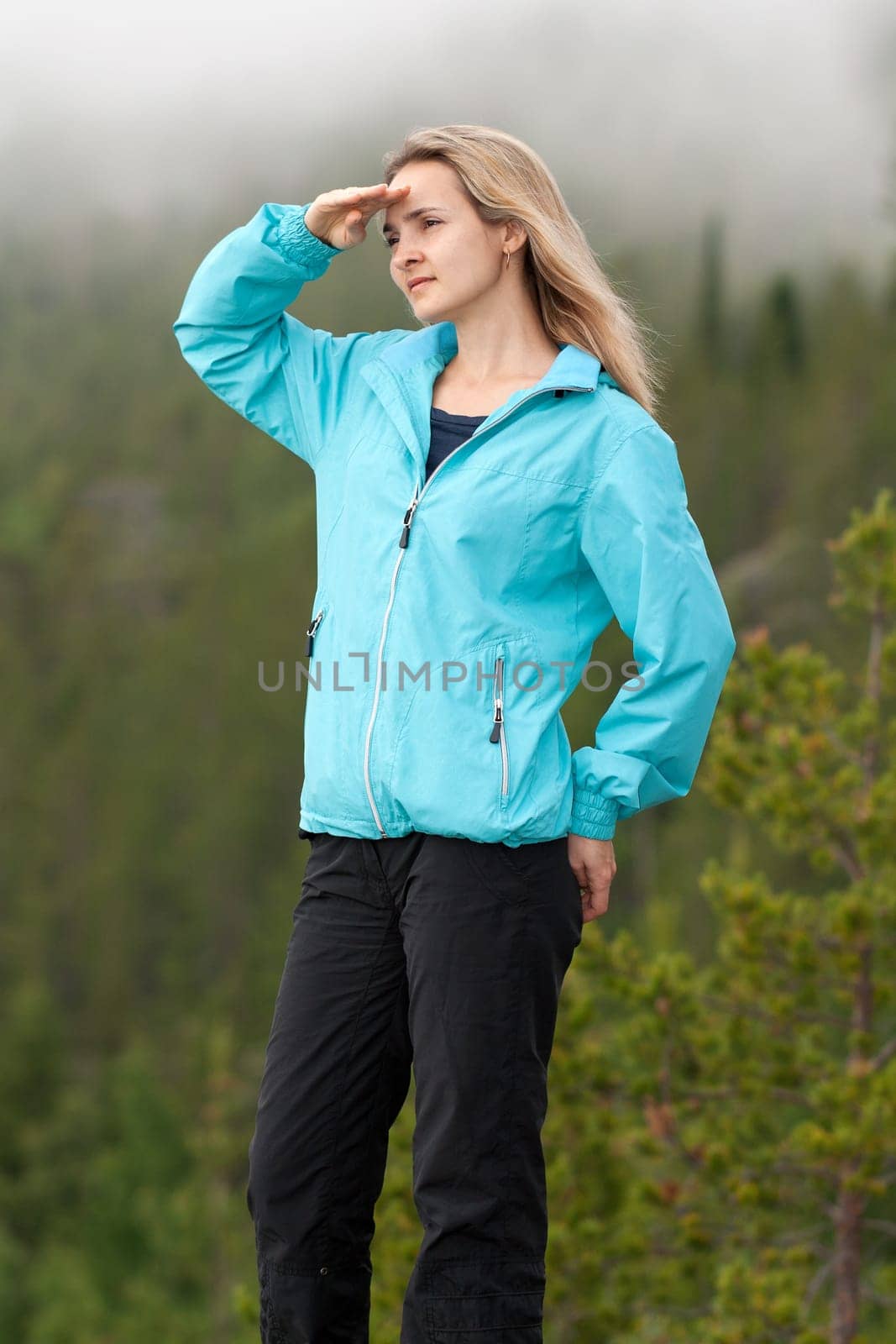 beautiful girl looks into the distance on the background of pine forest with fog